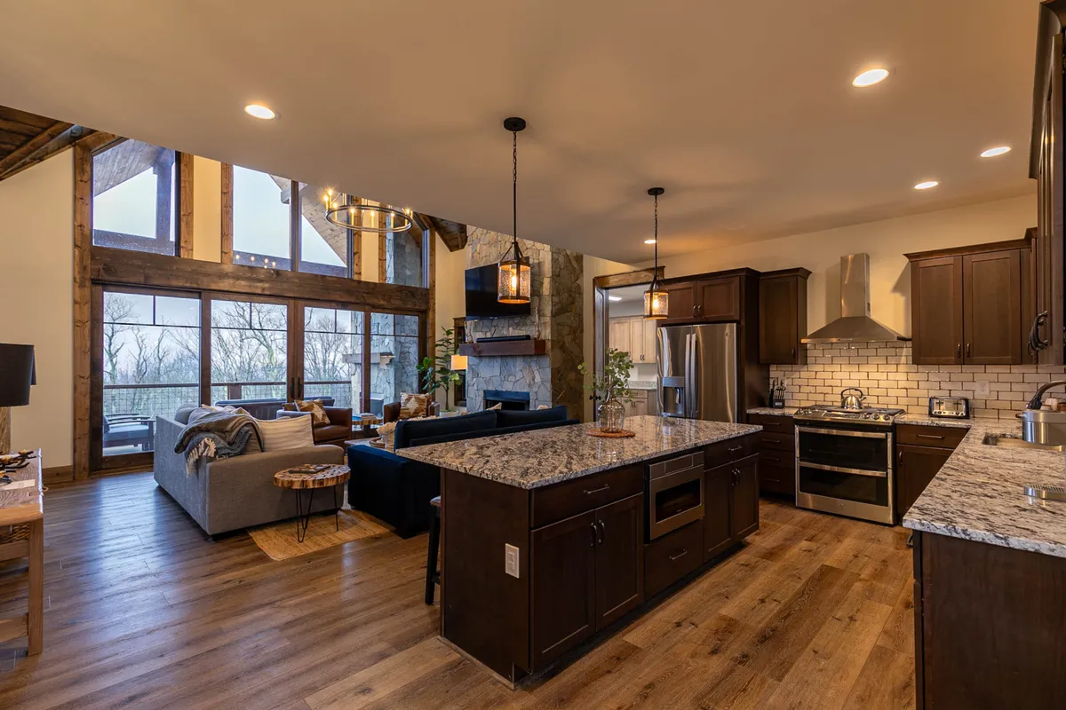 An open-plan living space featuring a granite countertop, large windows with ample natural light, a fireplace, and a comfortable seating area. The layout encourages socializing, dining, and enjoying the company of loved ones, with views connecting the indoors to the peaceful natural surroundings.