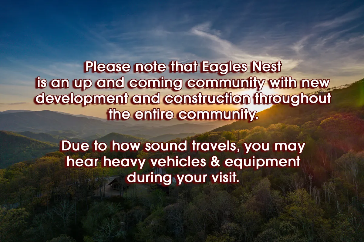 A sweeping view of a mountainous landscape at sunset, with a subtle construction notice in the corner. The scene emphasizes the natural beauty and outdoor adventure opportunities surrounding the community. The rolling terrain, woodland, and expansive sky hint at numerous trails and explorations awaiting visitors.