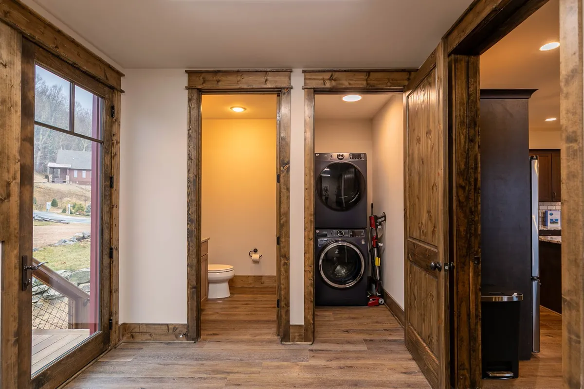 A practical laundry zone with a washer, dryer, wooden trim, and multiple doorways. The space is designed for efficiency and order, contributing to the home's overall cleanliness. Its organizational features support daily routines, including gear cleanup after outdoor adventures.